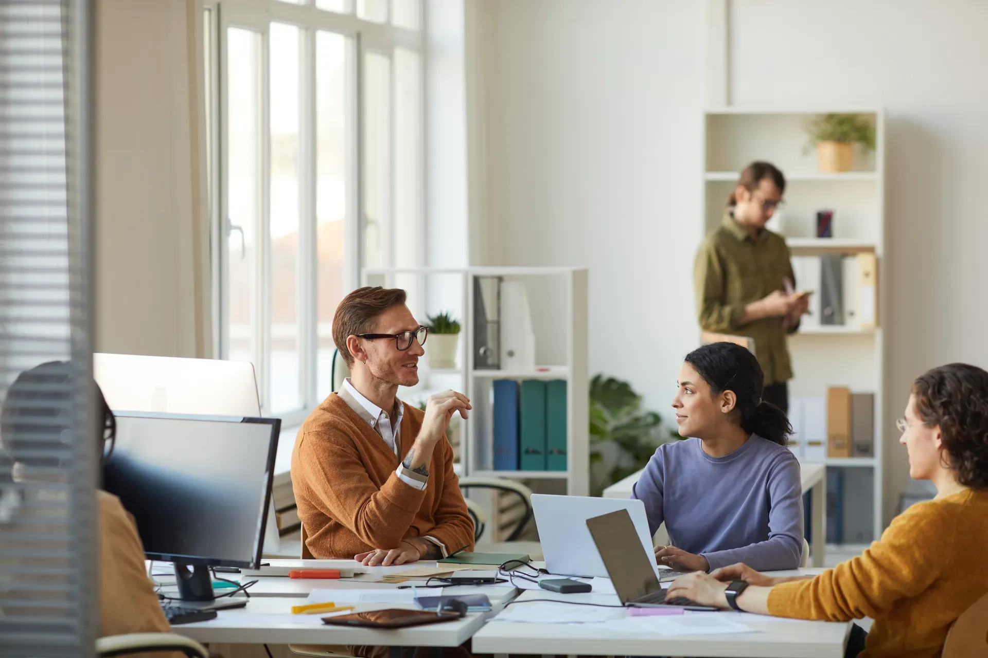 Collega's in gesprek aan bureaus in een licht kantoor