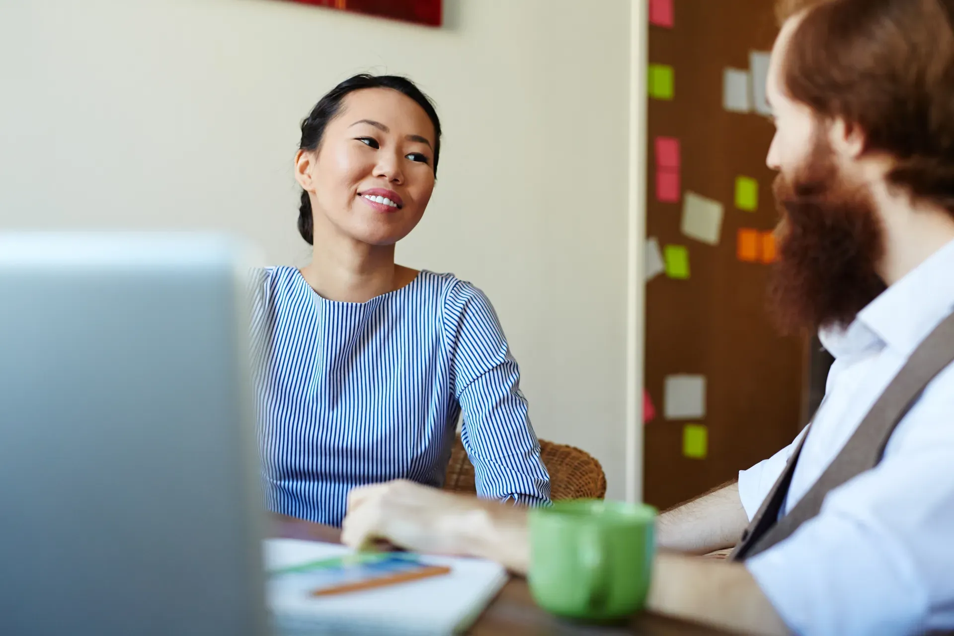 Twee mensen bespreken iets aan een werkplek met laptop