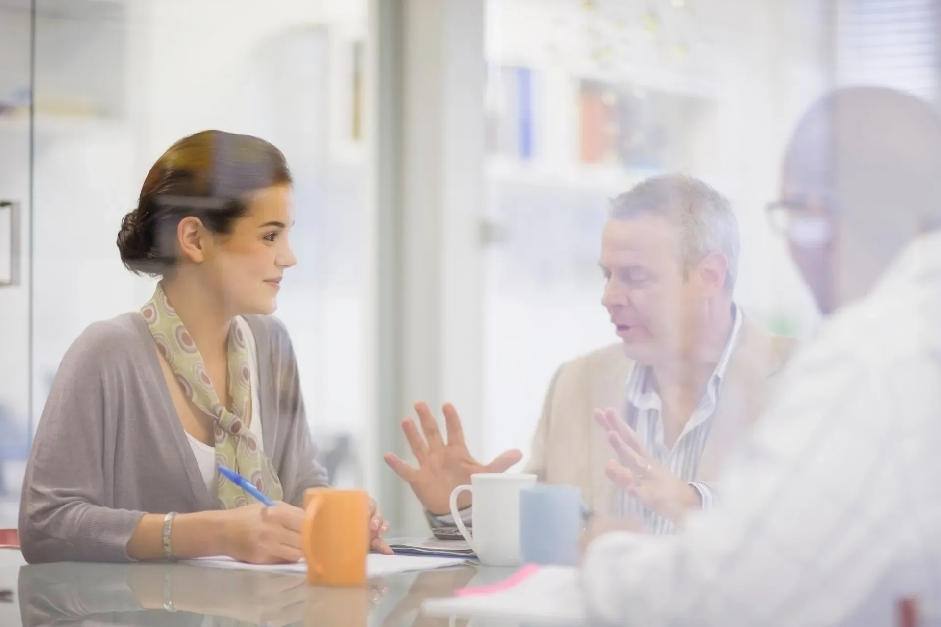 Adviesgesprek aan een tafel met koffiebekers en notities