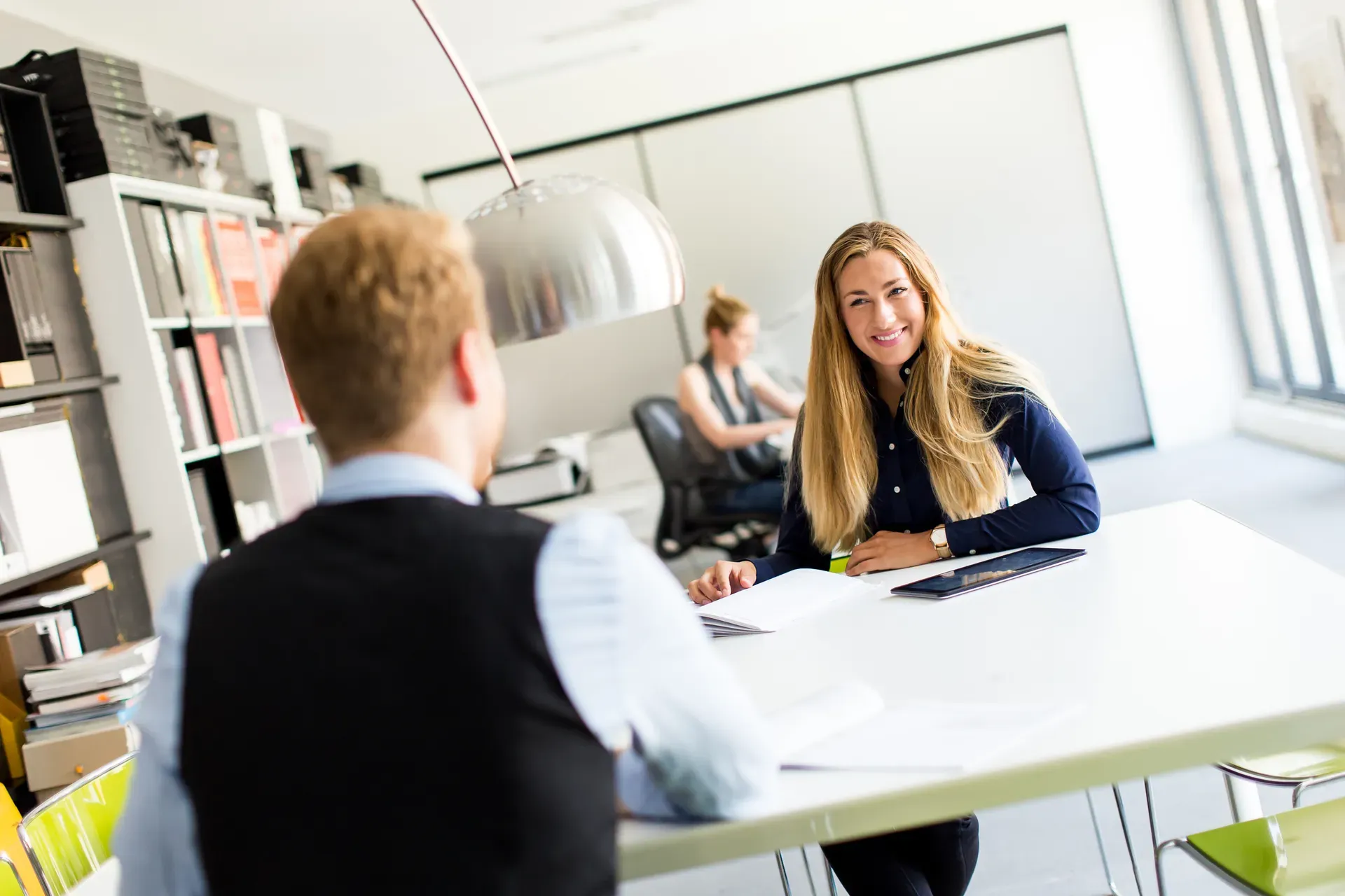 Twee mensen in gesprek aan een tafel in een kantoor